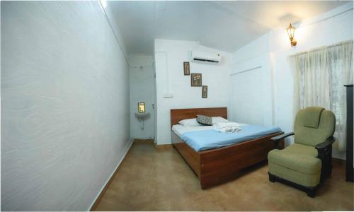 ein kleines Schlafzimmer mit einem Bett und einem Stuhl in der Unterkunft Waves and Shores Beach Villa in Mararikulam