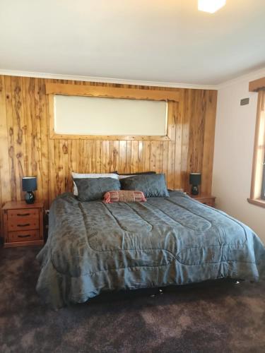 a bedroom with a large bed with a wooden wall at the tigers lair accomadation in Mole Creek