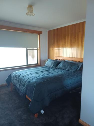 Schlafzimmer mit einem Bett mit einem Kopfteil aus Holz und einem Fenster in der Unterkunft the tigers lair accomadation in Mole Creek
