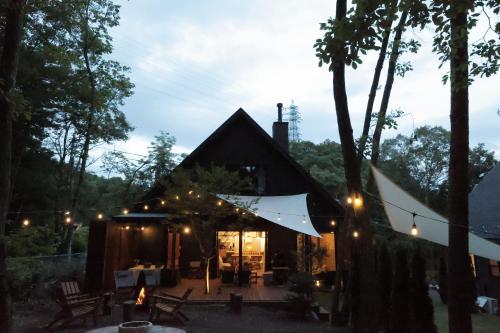 a cabin in the woods at night with lights at SAUNA FOREST CABIN 軽井沢 御代田 A棟 zen-asobi in Oiwake