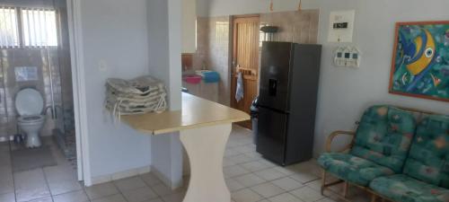 eine Küche mit einem Kühlschrank, einem Tisch und einem Stuhl in der Unterkunft Neptune corner cottage 10 in Hibberdene