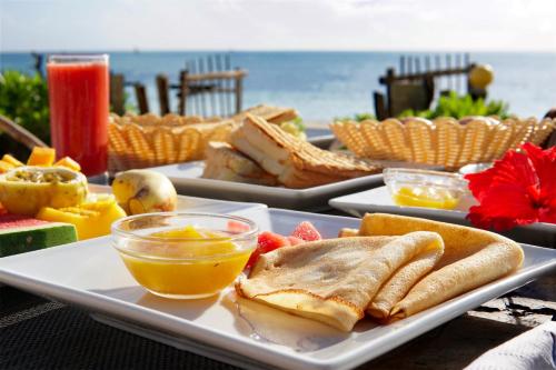 a table with a plate of food with sandwiches and fruit at Belvedere Resort in Jambiani