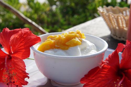 a bowl of ice cream and red flowers on a table at Belvedere Resort in Jambiani