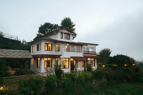 a large white house with its lights on at SaffronStays The Clairmont Cottage,Mukteshwar in Mukteshwar