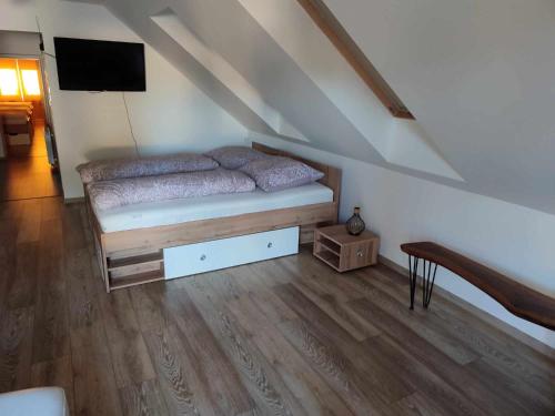 - une chambre mansardée avec un lit et une télévision dans l'établissement Apartmán Tulipán, à Hnúšťa