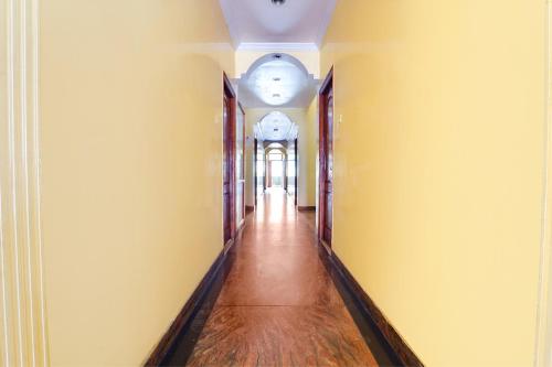 an empty hallway with yellow walls and wooden floors at Hotel Orchid Inn in Ooty