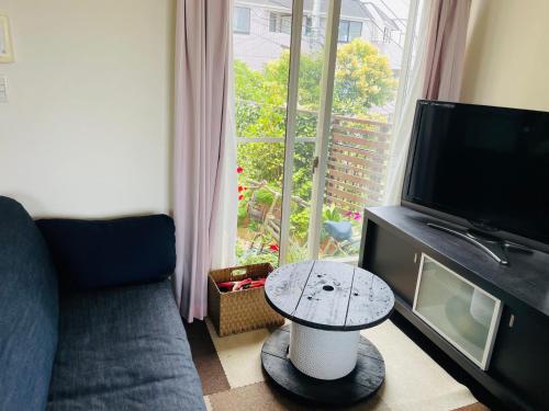 sala de estar con sofá, mesa y ventana en 横浜 JS HOUSE Yokohama - ペット犬可, en Yokohama