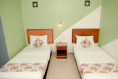 two twin beds in a room with two tables at HOTEL D VIEW MERSING in Mersing