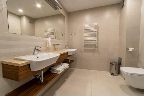 a bathroom with two sinks and a toilet at Hotel Wolin in Międzyzdroje