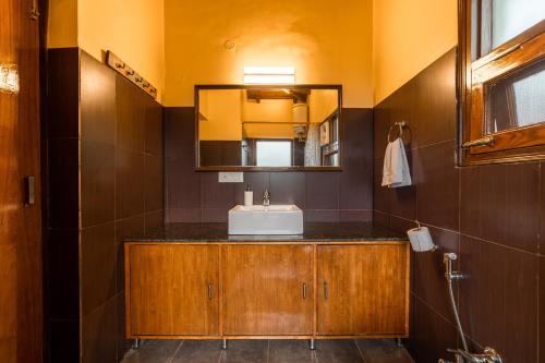 une salle de bain avec un lavabo et un miroir dans l'établissement SaffronStays The Clairmont Cottage,Mukteshwar, à Mukteswar