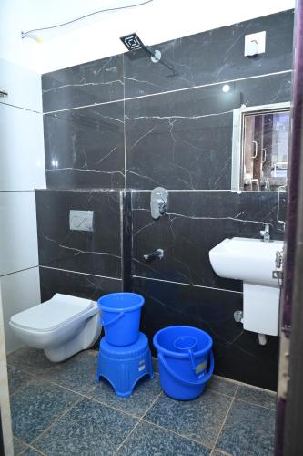 a bathroom with a toilet and a sink and buckets at Blue Pearl Beach Guest House in Māvalli