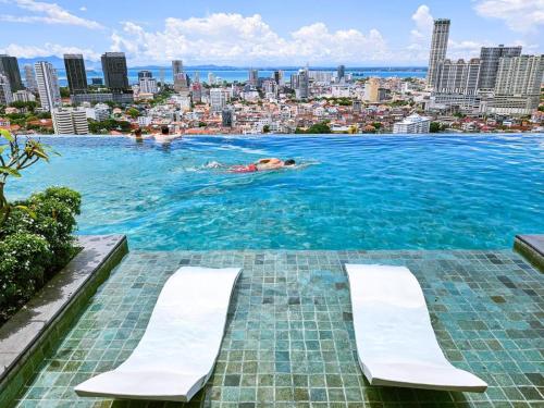 a person swimming in a large pool with a city in the background at Beacon Executive Suites in George Town