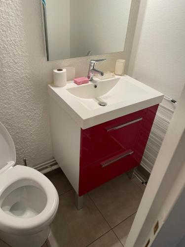 La salle de bains est pourvue d'un lavabo rouge et blanc et de toilettes. dans l'établissement Alpe d Huez 6 pers appart, à Huez