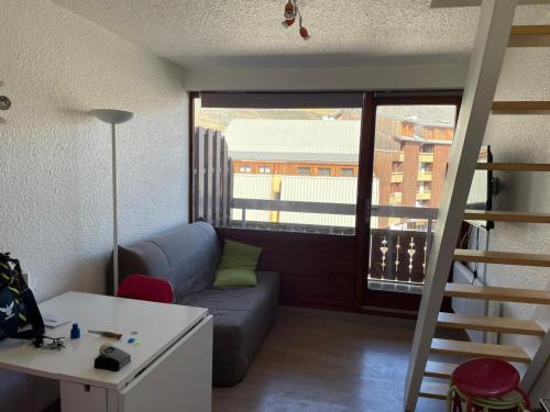 a living room with a couch and a ladder to a window at Alpe d Huez 6 pers appart in LʼHuez