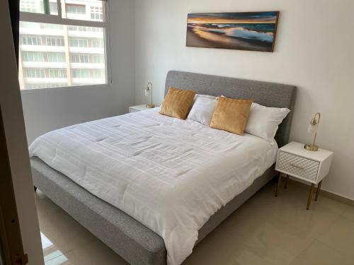 a bedroom with a large bed with white sheets at Hermoso Departamento frente al Mar in Tijuana