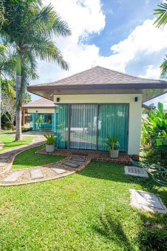 a house with a green lawn and palm trees at Phuket Boutique Pool Villa-81 in Rawai Beach