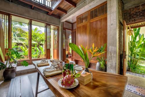 a dining room with a wooden table and some plants at Faifo Retreat Villa Hội An in An Bang