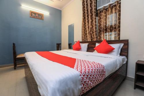 een slaapkamer met een groot bed met rode kussens bij OYO New Airport Residency in Jaipur