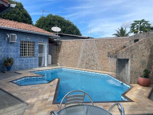 a swimming pool in a backyard with a stone wall at MiniRooms in Boa Vista