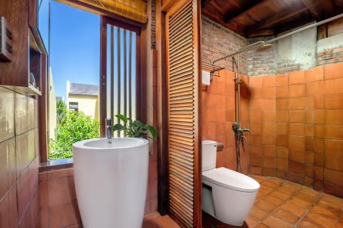 a bathroom with a toilet and a sink and a window at Faifo Retreat Villa Hội An in An Bang