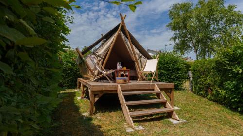 Camping Vittel في فيتيل: خيمة مع كرسي وطاولة في العشب