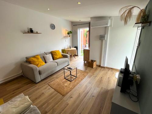 uma sala de estar com um sofá cinzento e almofadas amarelas em Charmant bungalow climatisé avec jacuzzi em Sainte-Clotilde
