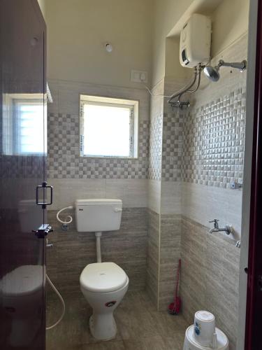 een badkamer met een toilet en een douche en een raam bij Jothi Residency in Madurai