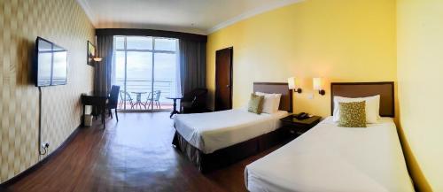 a hotel room with two beds and a balcony at EHSAN SEAVIEW HOTEL PORT DICKSON in Port Dickson