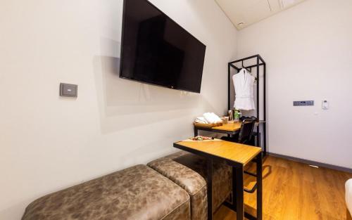 a living room with a couch and a television on the wall at Hotel The Artist Yeonsinnae in Seoul