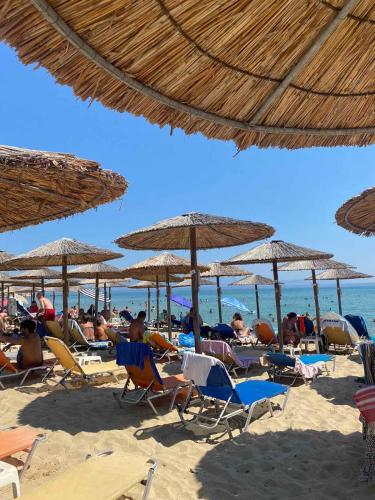 a group of people sitting on the beach under umbrellas at ''Mary's House'' Entire residence Olympiada Halkidiki Near to Sea 200m ! in Olympiada