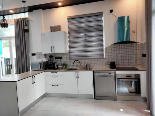 une cuisine avec des armoires blanches et des appareils en acier inoxydable dans l'établissement Florence Villas, à Jaffna