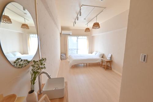Una habitación blanca con una cama y un espejo. en 小春日和_沖繩_松山館, en Naha