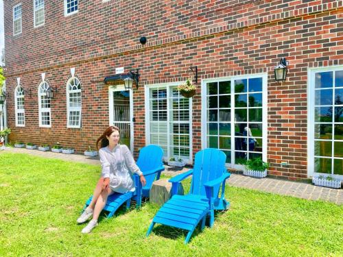 a woman sitting on chairs in front of a brick building at 墾丁勿忘我城堡莊園 in Hengchun