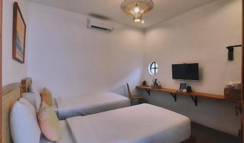 a hotel room with two beds and a television at Betah Homestay Banyuwangi in Banyuwangi