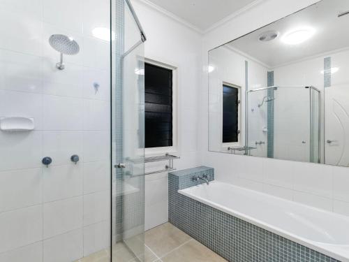 La salle de bains est pourvue d'une baignoire et d'une douche en verre. dans l'établissement SlipStream By The Sea, à Casuarina