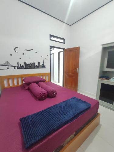 Home Syariah Guest House Ampana في Dondo: غرفة نوم مع سرير بملاءات ووسائد أرجوانية