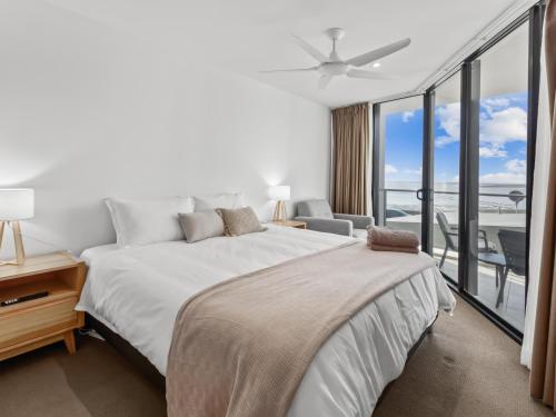 Un dormitorio blanco con una cama y un balcón. en Pier One Waterfront Apartment, en Urangan