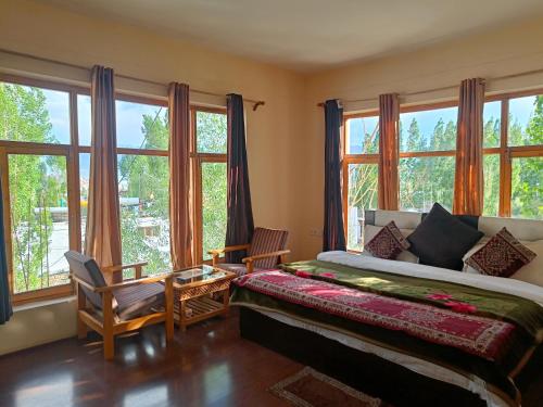 a bedroom with a bed and large windows at Hotel Malik Residency in Leh