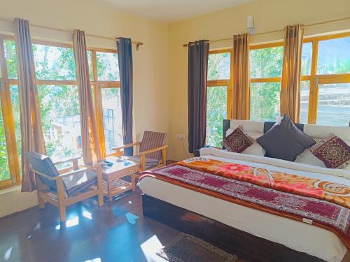 a bedroom with a large bed and windows at Hotel Malik Residency in Leh