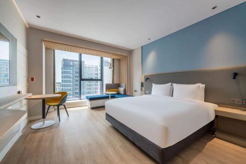 Una habitación de hotel con una gran cama blanca y un escritorio. en Holiday Inn Express Zhoukou Dancheng by IHG, en Zhoukou