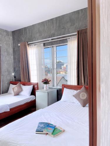 een hotelkamer met 2 bedden en een raam bij Amy Hostel Hue in Hue