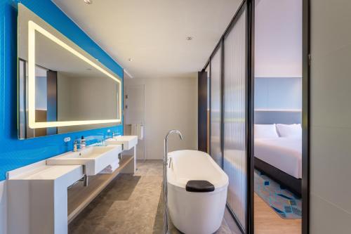 uma casa de banho com 2 lavatórios, uma banheira e uma cama. em Holiday Inn Express Zhoukou Dancheng, an IHG Hotel em Zhoukou