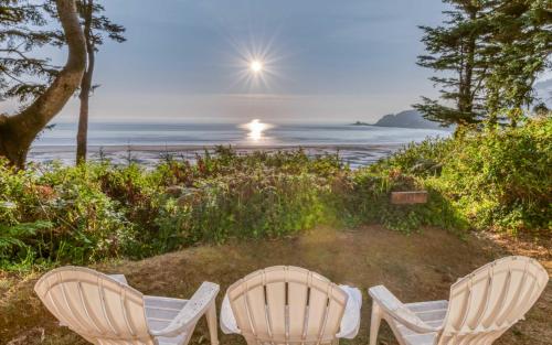 two chairs sitting next to the ocean with the sun in the sky at Agate Beach Oceanfront Suite B in Newport