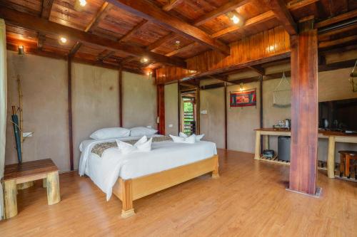 a bedroom with a white bed in a room with wooden ceilings at Mai Chau Onsen Retreat in Mai Chau
