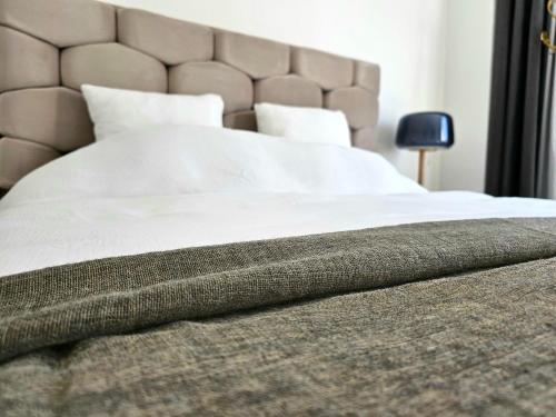 een bed met witte lakens en een bruin hoofdeinde bij Appartement Fernand Namur in Namen