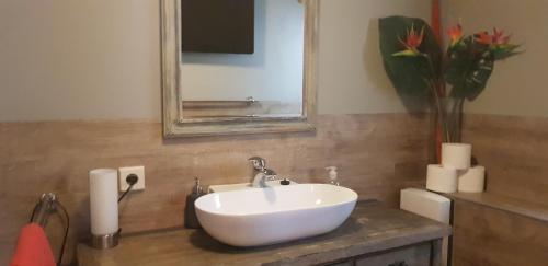 ein Badezimmer mit einem weißen Waschbecken und einem Spiegel in der Unterkunft Die drei Haselnüsse in Nazza
