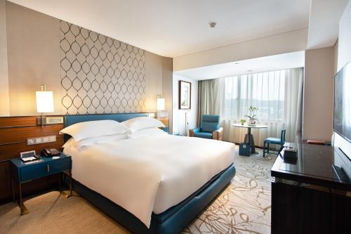 廈門市にある厦門 エアラインズ レイクサイド ホテルの大きなベッドとデスクが備わるホテルルームです。