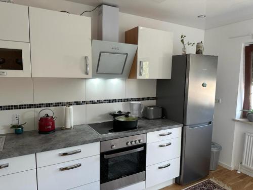 eine Küche mit weißen Schränken und einem Kühlschrank aus Edelstahl in der Unterkunft Lichtdurchflutete 90 m2 drei Zimmer Duplexwohnung in Altperlach in München