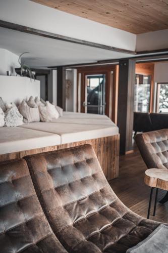 a bedroom with a large bed and a chair at Alpin Juwel - Bio und Lifestylehotel in Saalbach Hinterglemm
