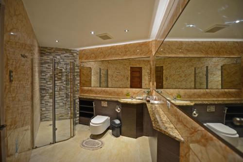 ein Badezimmer mit zwei Waschbecken, einem WC und einer Dusche in der Unterkunft Bellagio Hills Hotel and Restaurant in Paoay